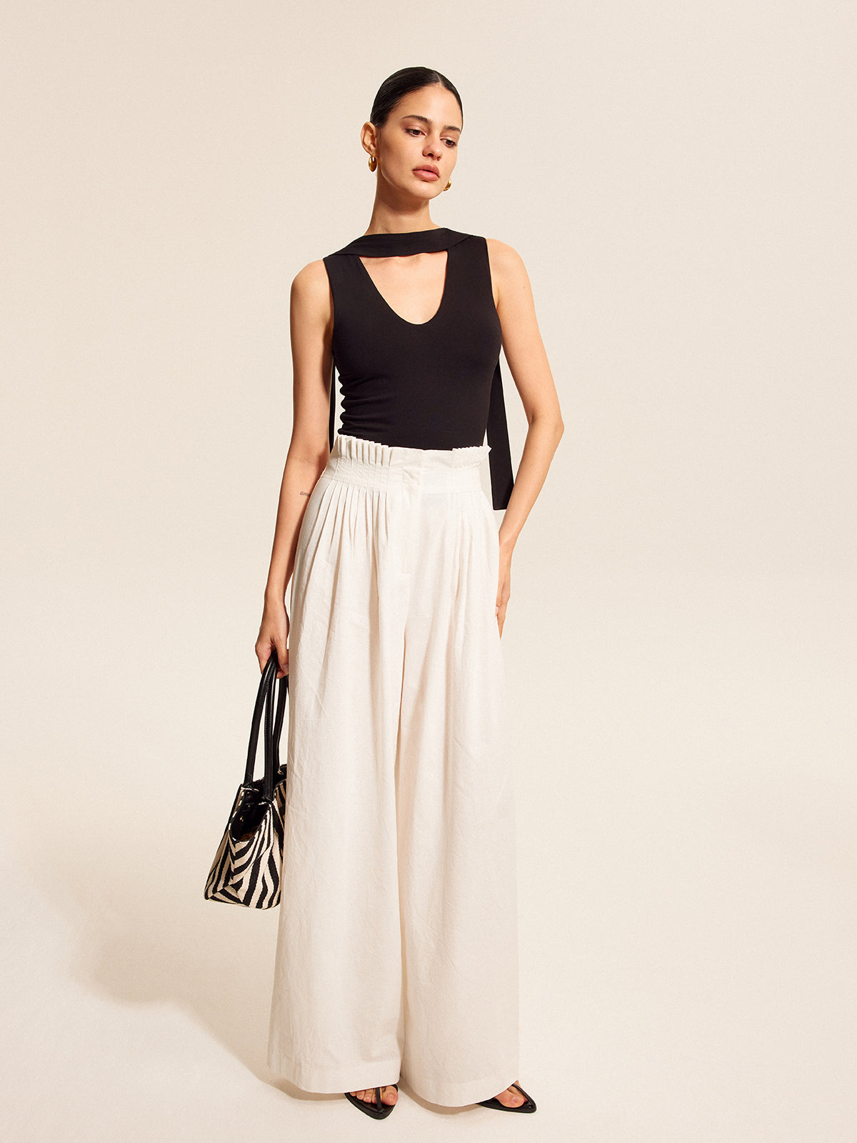 V-neck blouse with elegant scarf-style neck tie paired with wide-leg white pants.