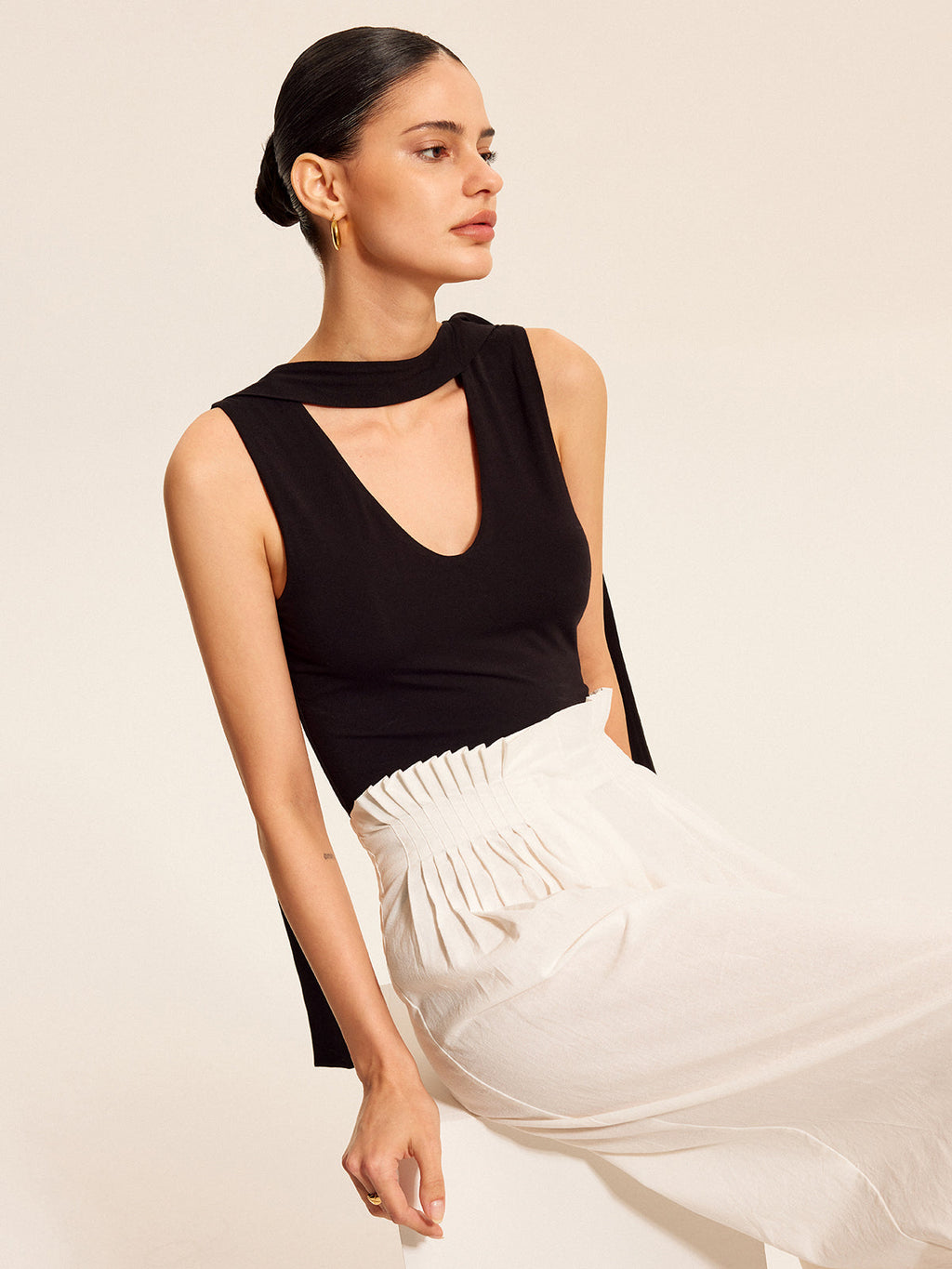 V-neck blouse with elegant scarf-style neck tie, paired with high-waisted white pants.