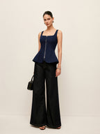 Zip-up denim peplum blouse with waist detail and wide-leg dark jeans.