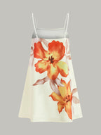 Sleeveless, oversized cream mini dress with white straps and bold orange-yellow floral prints.