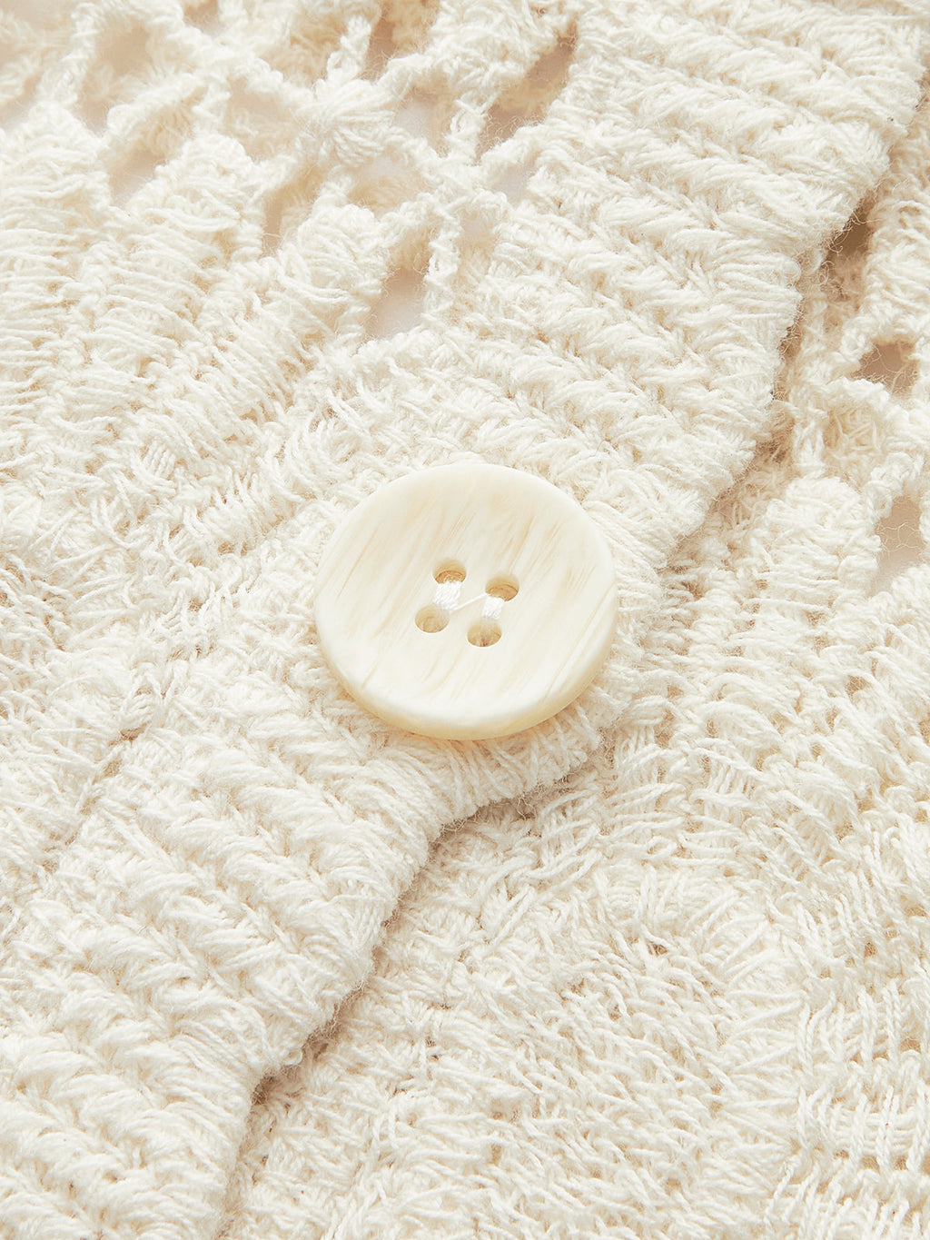 Cream floral crochet cardigan with button-up front and prominent large, round four-hole button.