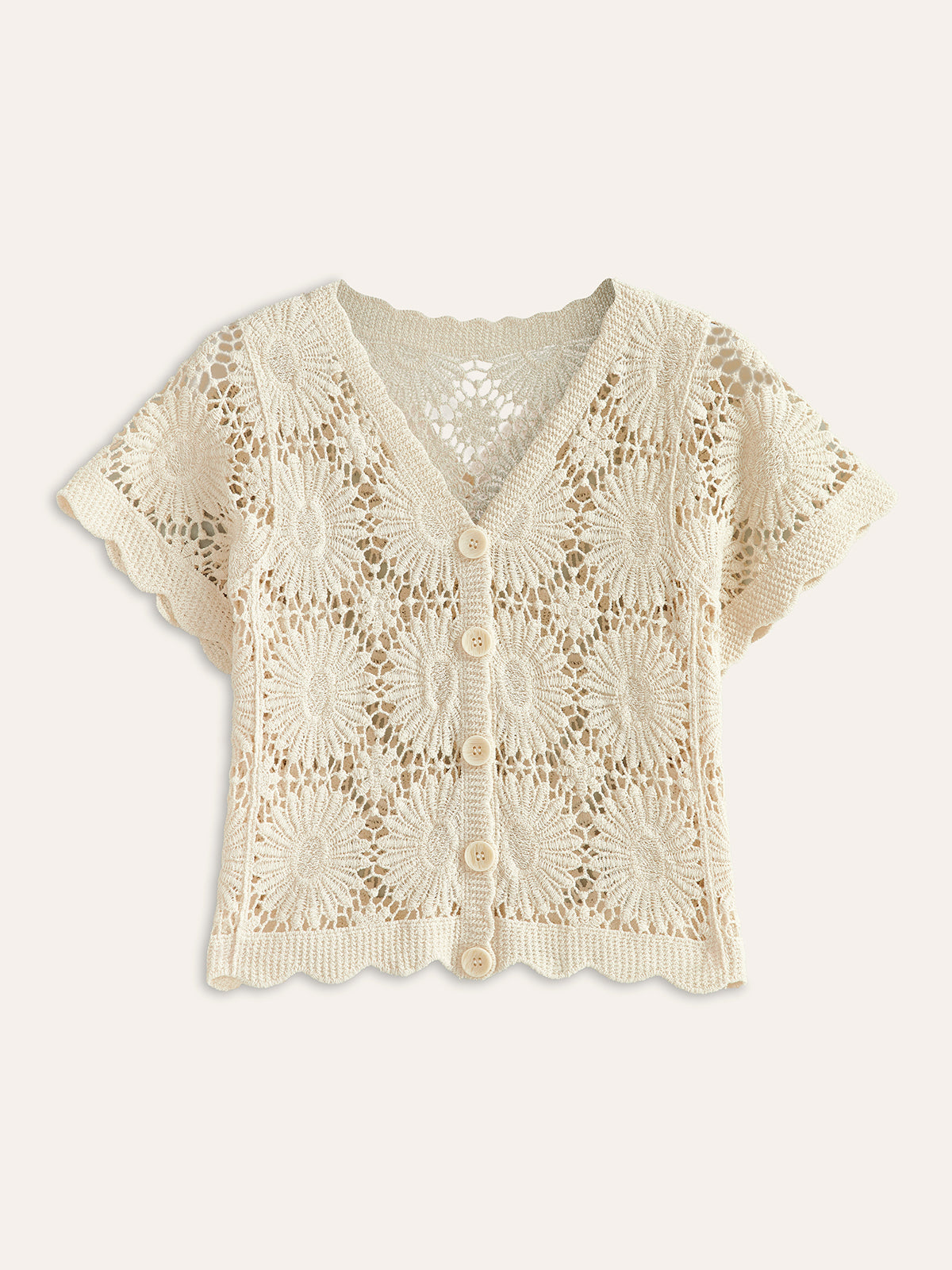 A cropped cream knit cardigan with floral crochet designs, short sleeves, v-neck, button-up front.