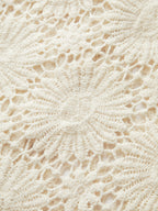 Cream-colored crocheted cardigan with floral lace pattern and intricate button-up design details.