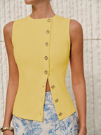 LA FINE FLEUR Asymmetric Closure Textured Knit Vest with gold buttons and blue floral skirt.