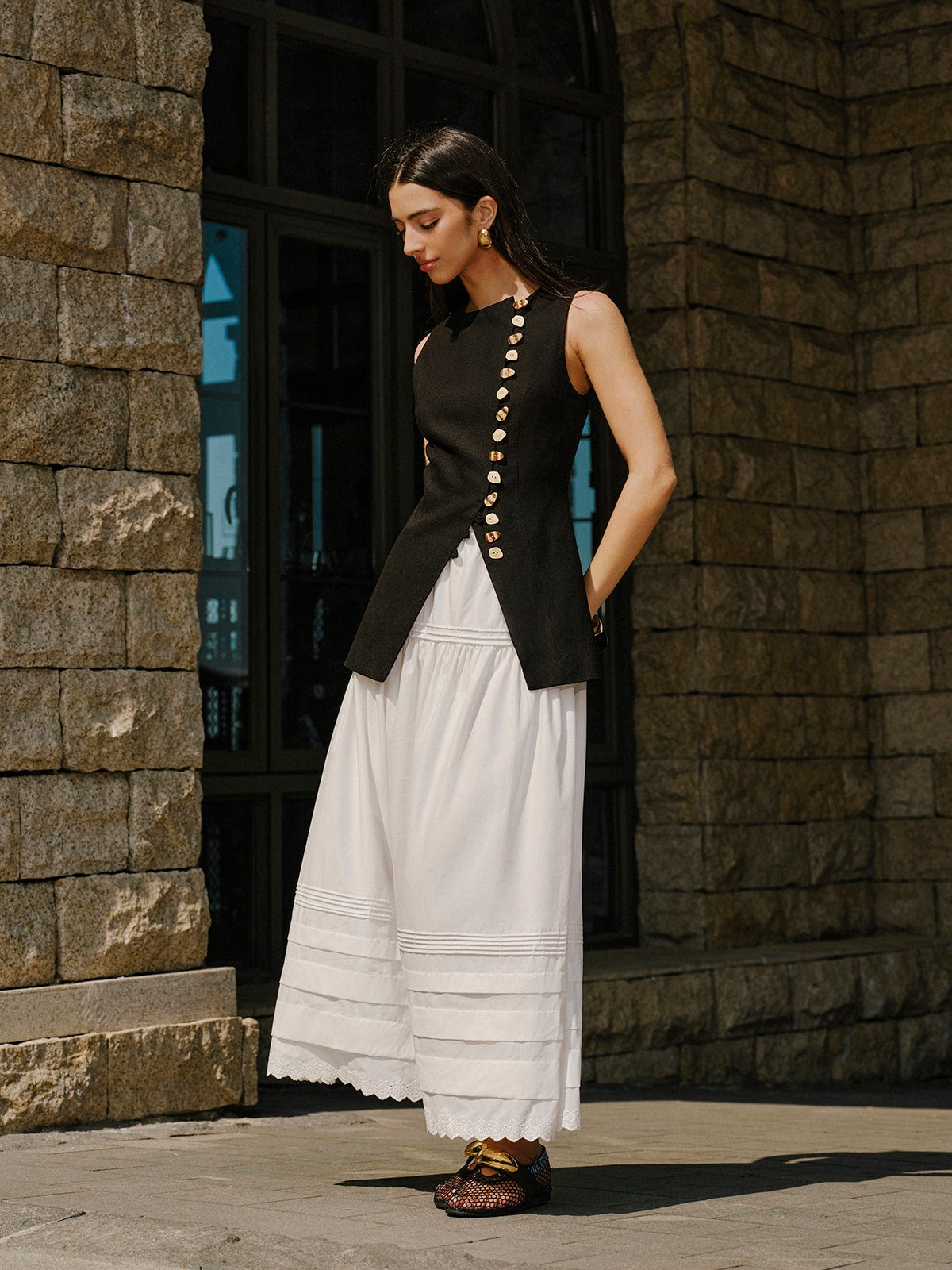 Linen vest with elegant button details, layered over a white tiered maxi skirt.