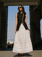 A linen vest with elegant button details styled with a long, pleated white skirt.