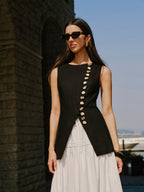 Black LA FINE FLEUR linen vest with elegant button details over a white dress.