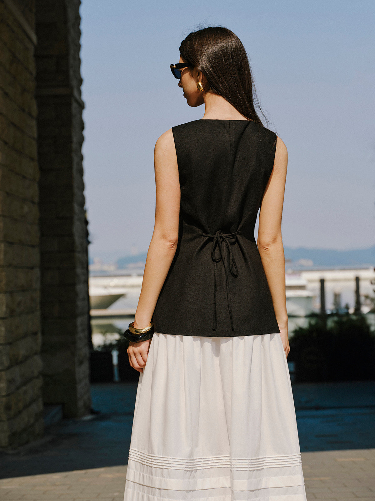LA FINE FLEUR Linen Vest with elegant button details and a long white skirt.