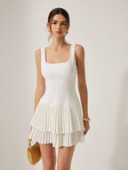 A chic mini dress with a square neckline, fitted bodice, and double-layered pleated skirt.