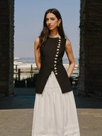 LA FINE FLEUR Linen Vest with elegant button details paired with a flowing white skirt.