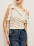 One-shoulder blouse with an elegant bow detail, paired with classic blue jeans.