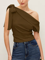 The LA FINE FLEUR one-shoulder blouse with elegant bow, styled with high-waisted blue jeans.