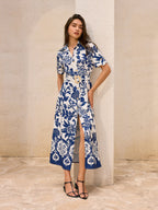 A blue floral print midi dress with a pocketed belt detail and front slit.