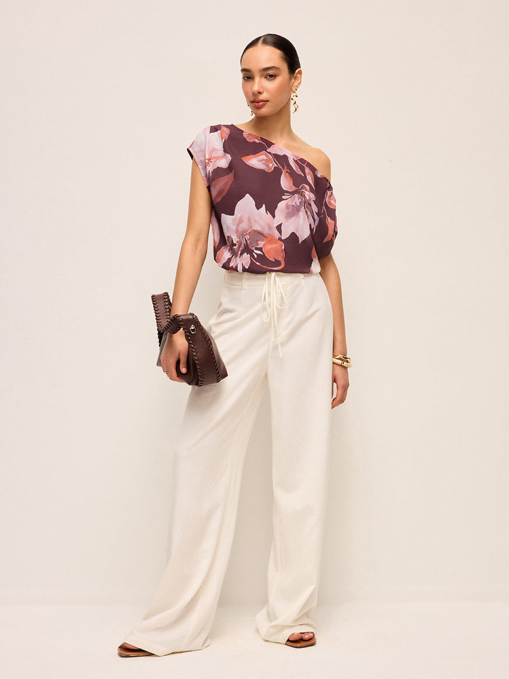 LA FINE FLEUR Floral One-Shoulder Blouse with Belt Detail paired with wide-leg white pants.