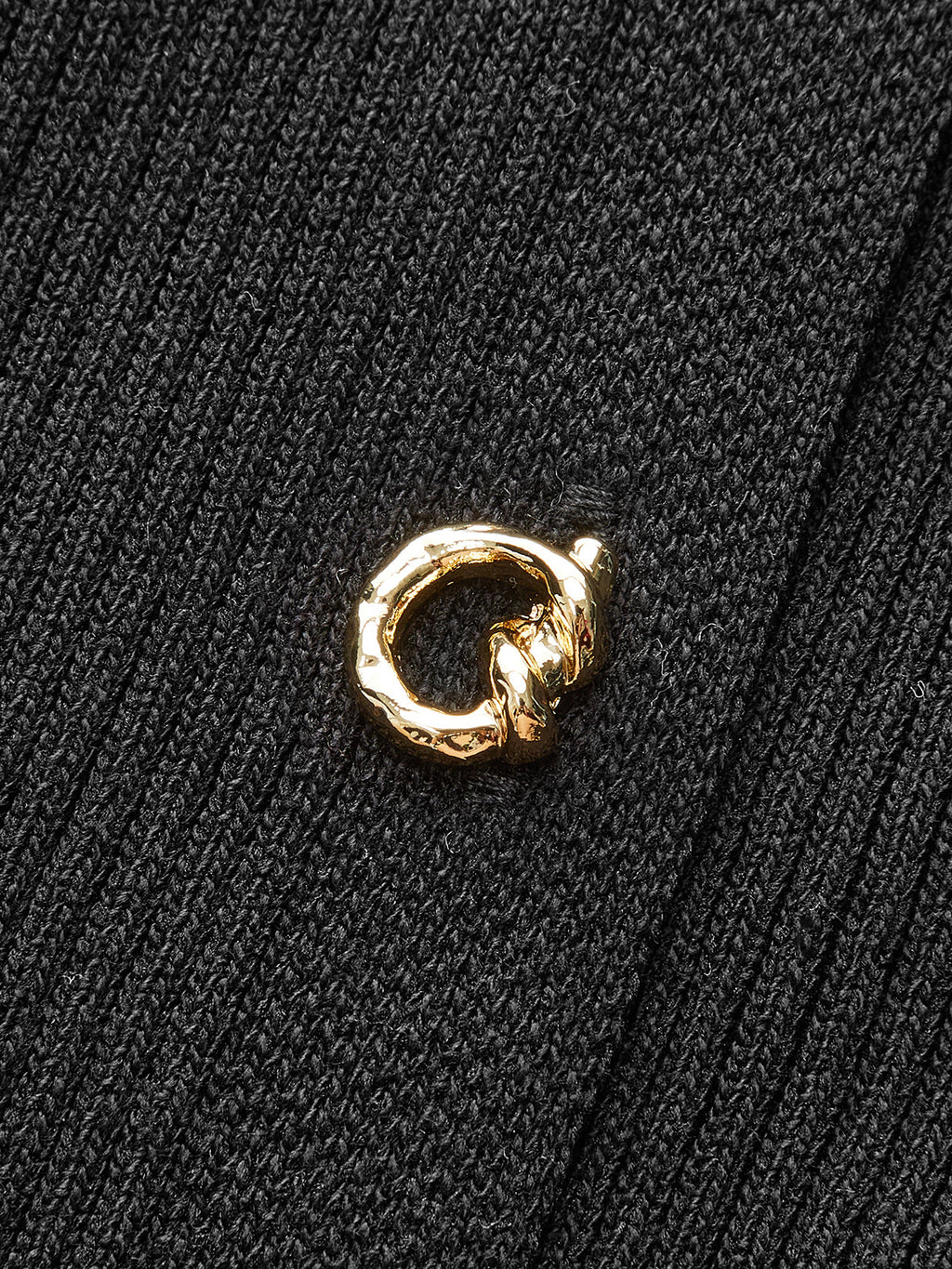 A black ribbed knit midi dress featuring button details and a small gold ring-shaped pin.