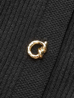 A black ribbed knit midi dress featuring button details and a small gold ring-shaped pin.