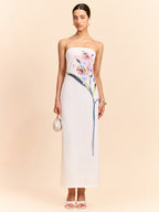 A white strapless maxi dress featuring an elegant floral design along the front panel.