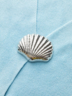 Close-up of a light blue knit vest with shell button and textured stitch detail.