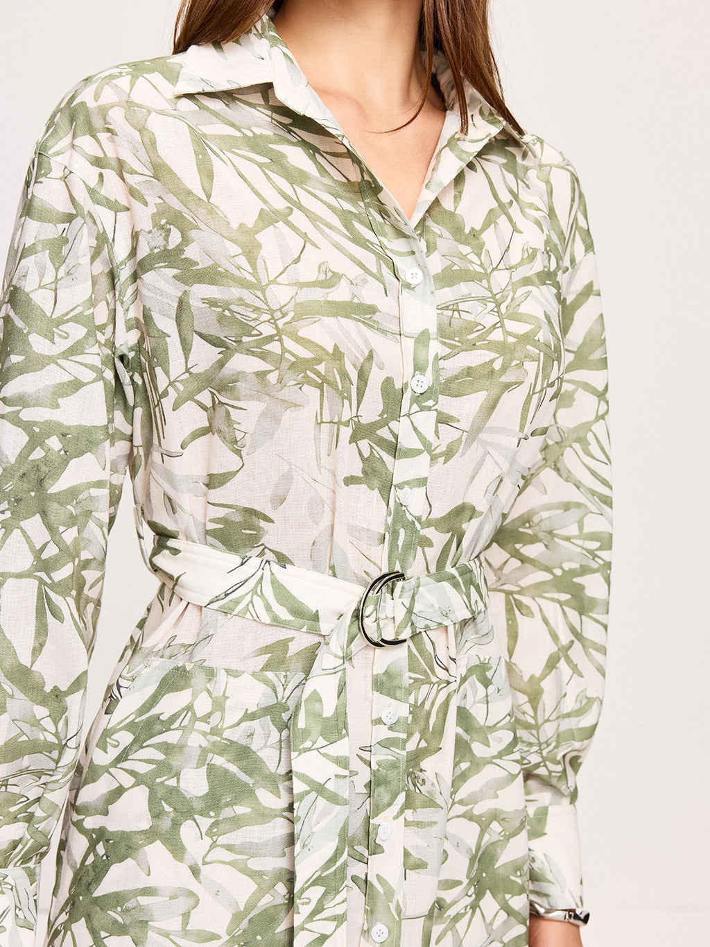 Green leafy print belted midi dress with long sleeves, collar, and side slits.