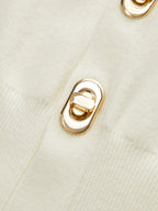Cream-colored BYPINKYPARIS knitted vest with textured fabric and shiny gold metallic buttons.