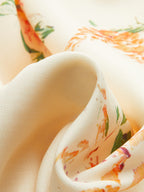 A sleeveless maxi dress in creamy-white fabric with orange, green, and purple watercolor florals.