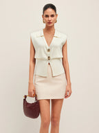 A beige mini skirt paired with a BYPINKYPARIS knitted vest featuring metallic buttons.