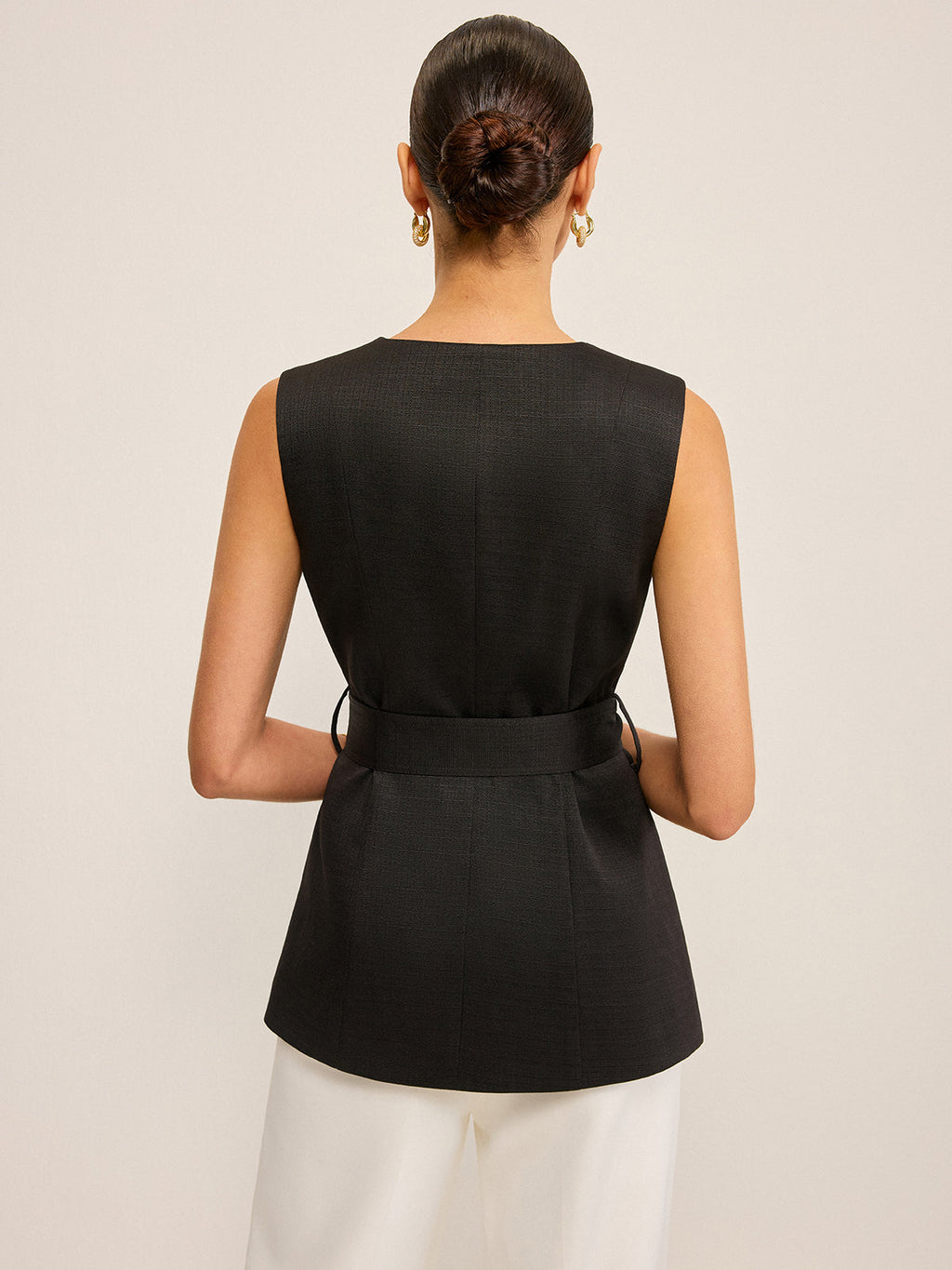 LA FINE FLEUR Sequin Floral Embellished Vest with Belt Detail and tailored white pants.