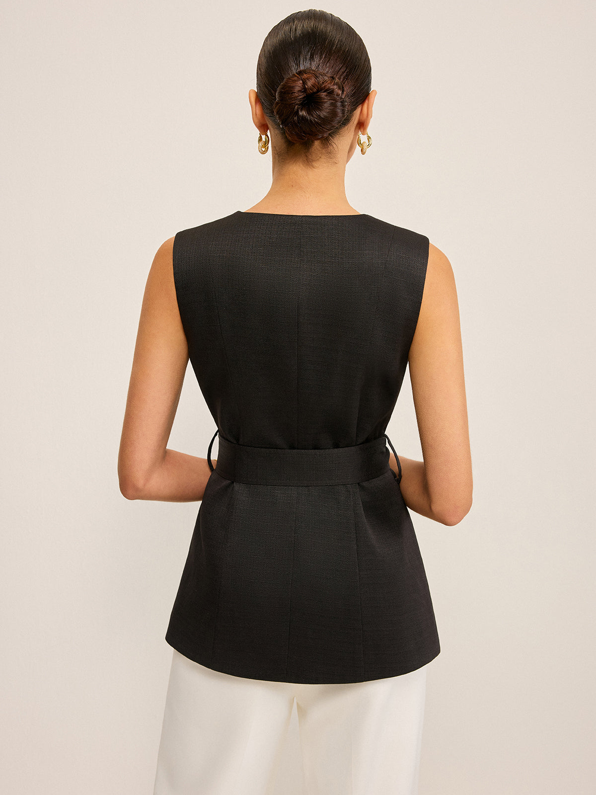 LA FINE FLEUR Sequin Floral Embellished Vest with Belt Detail and tailored white pants.