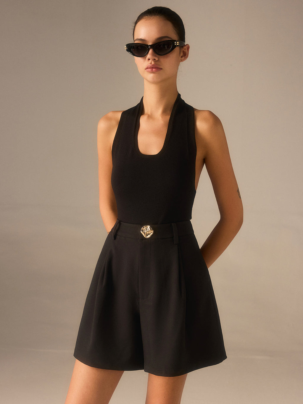High-waisted shorts with chic metallic details and a sleeveless black top.