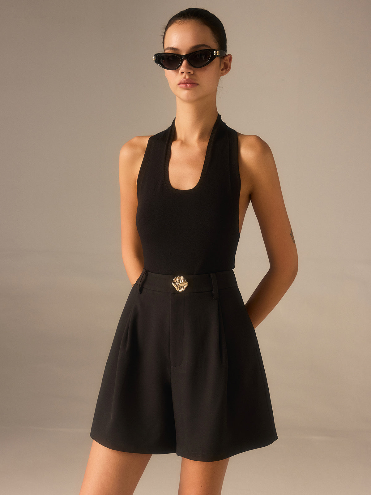 High-waisted shorts with chic metallic details and a sleeveless black top.