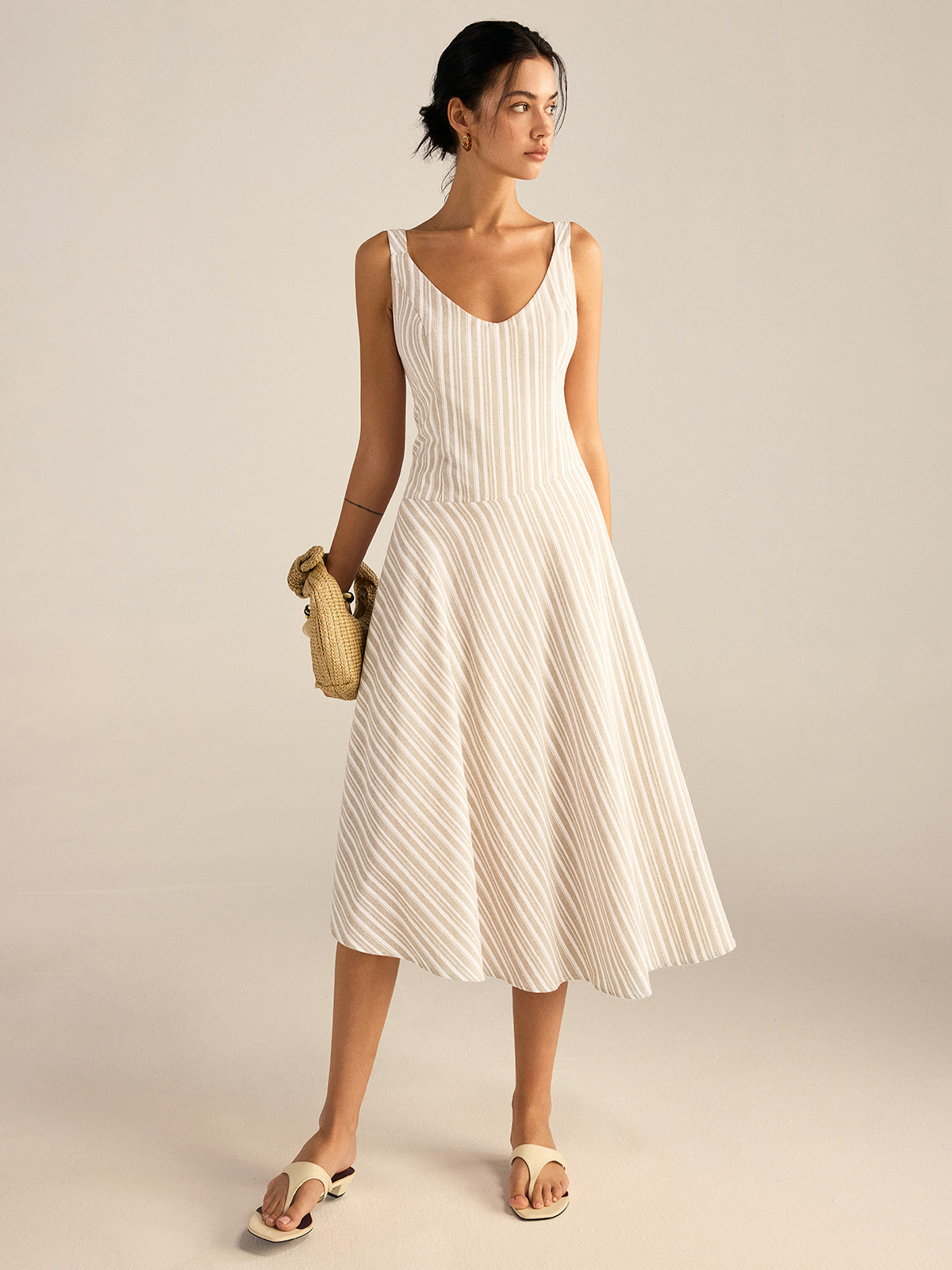 A midi dress with thin beige stripes and an asymmetrical hemline from LA FINE FLEUR.