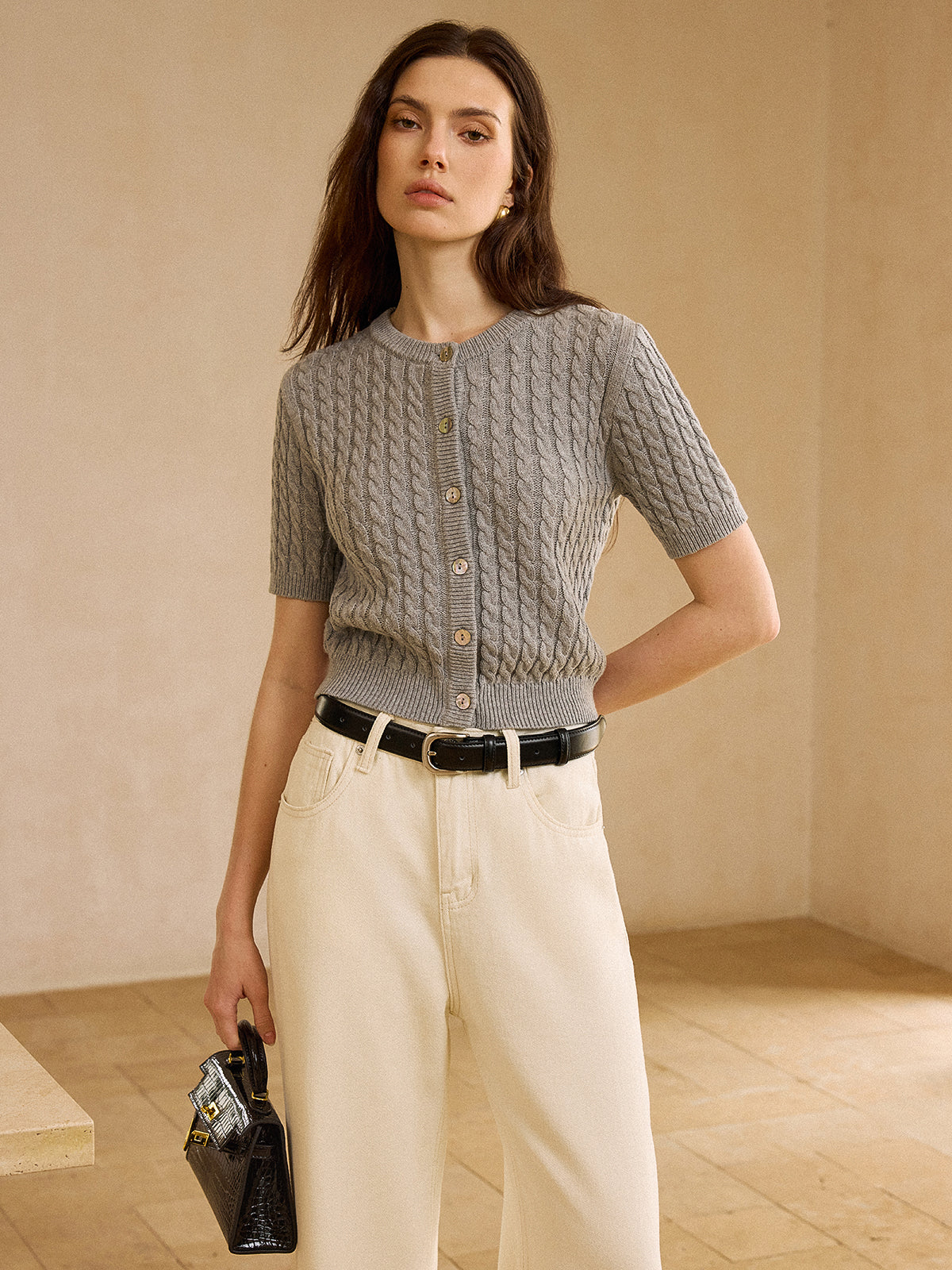 LA FINE FLEUR short-sleeve cable knit cardigan, cream high-waisted jeans, and black belt.
