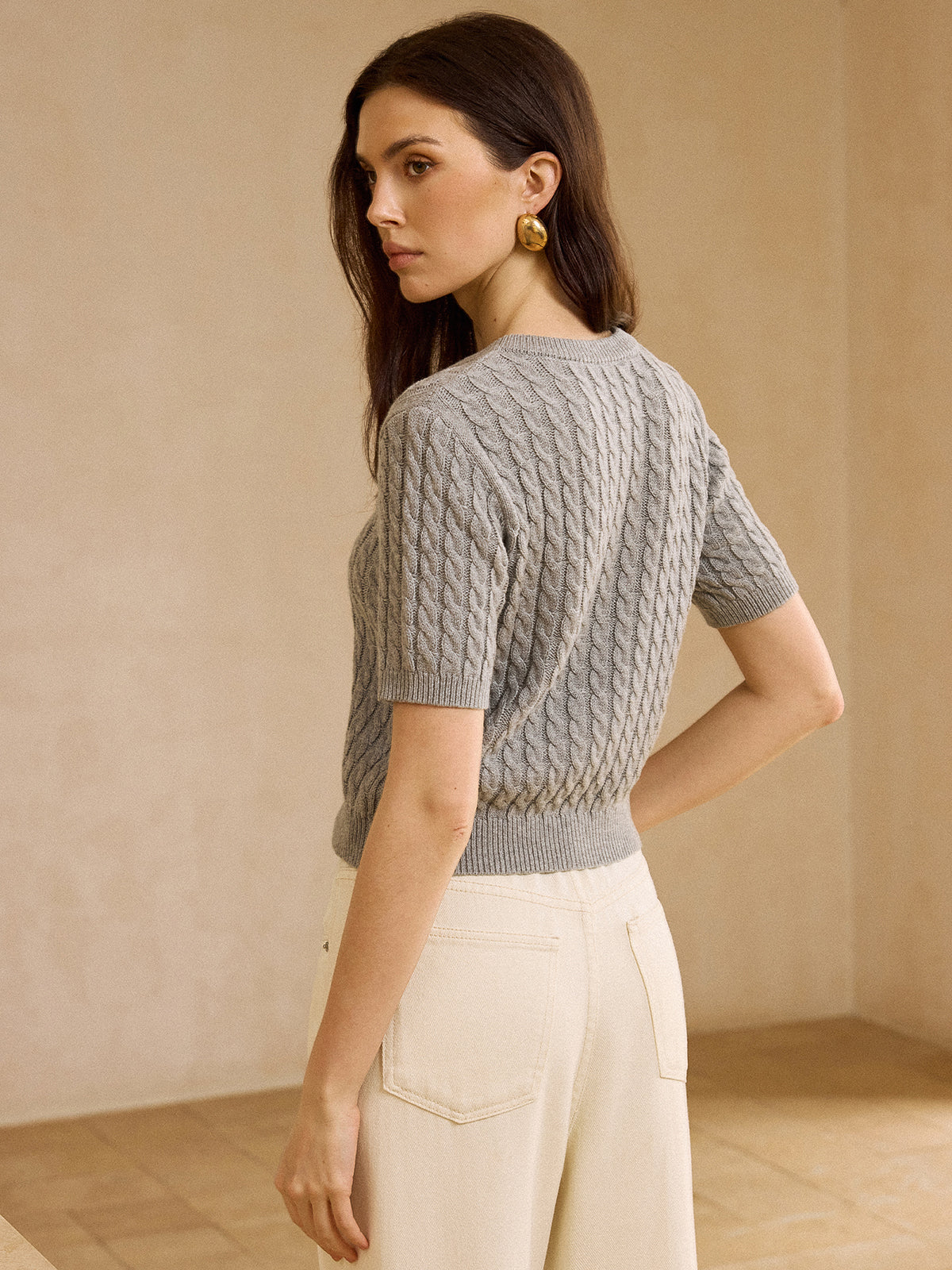 Short-sleeve cable knit cardigan sweater styled with high-waisted off-white pants.