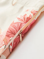 Mid-waist shorts featuring pink and cream floral fabric, tropical belt, and a light zipper pull.