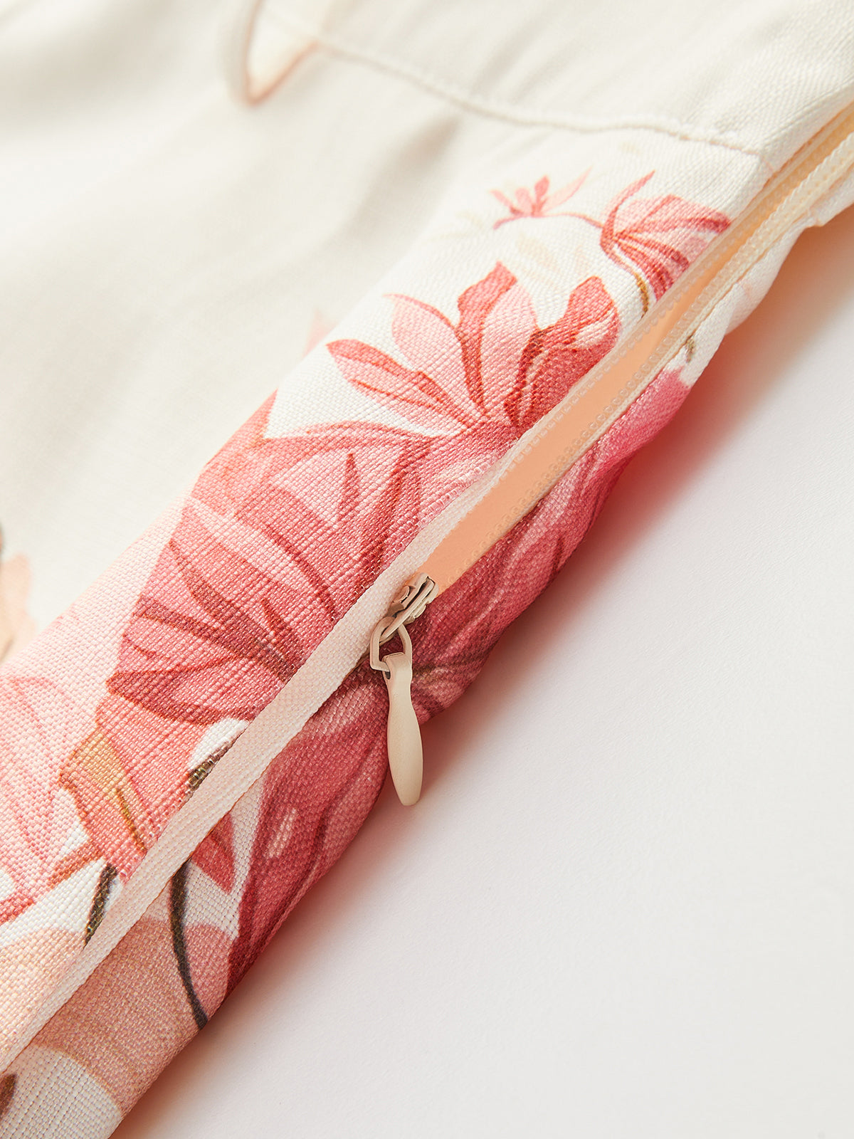 Mid-waist shorts featuring pink and cream floral fabric, tropical belt, and a light zipper pull.