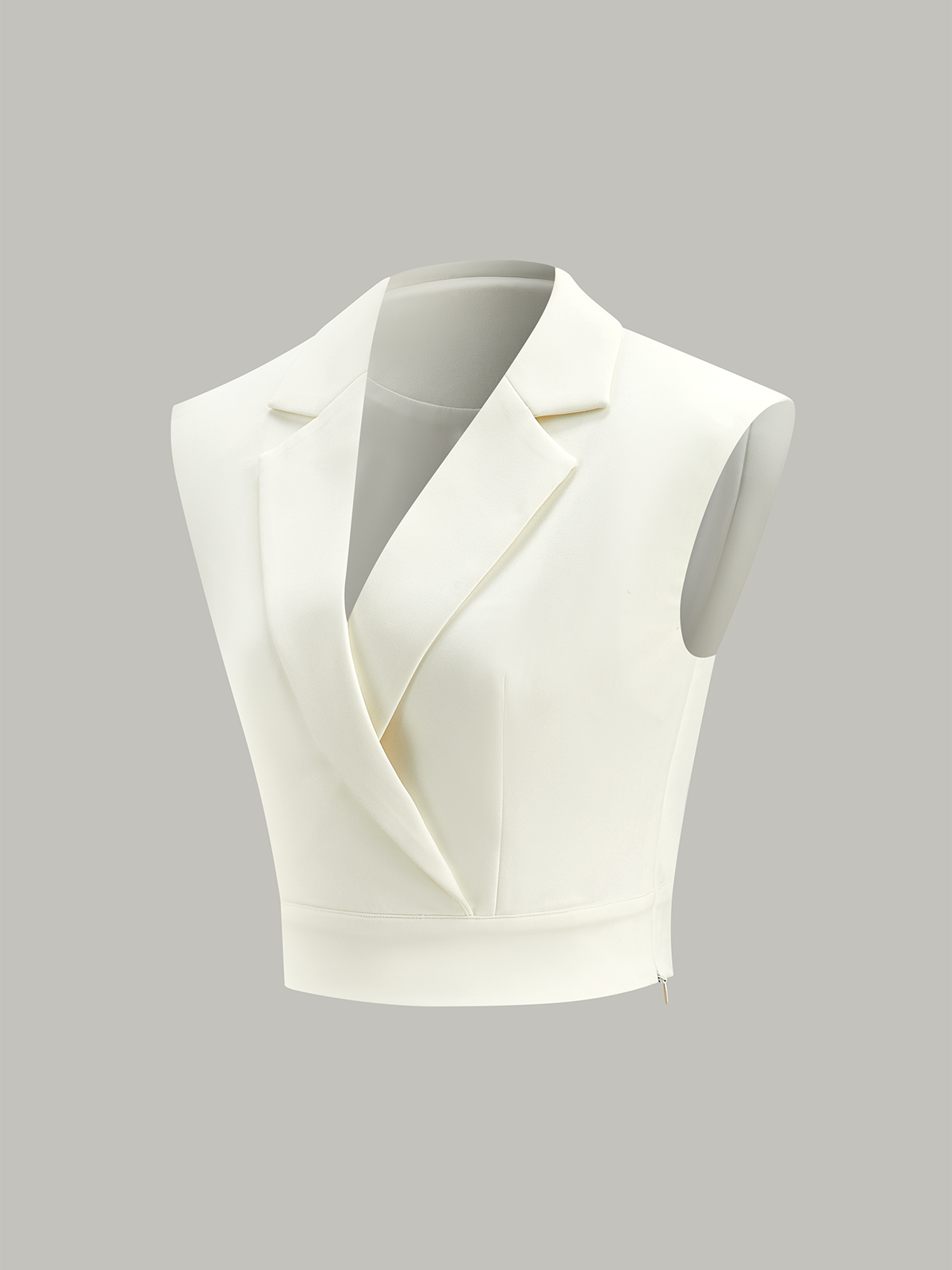 A white sleeveless cropped blazer vest with lapels, deep V-neck, cinched waist, hidden zipper.