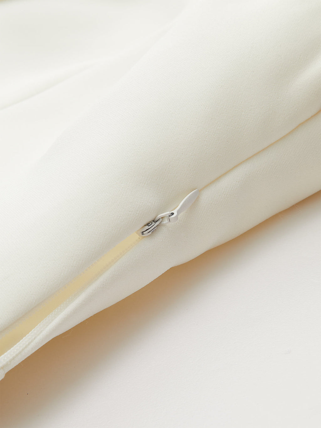 Wide-cut cropped blazer vest in cream, sleeveless, cinched waist, hidden zipper with white pull.