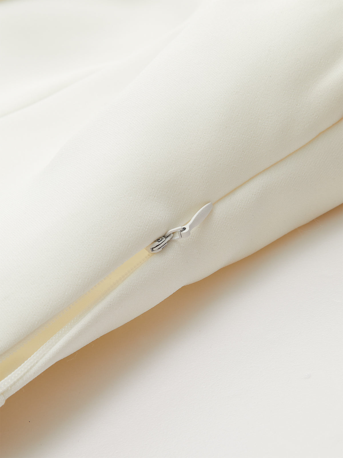 Wide-cut cropped blazer vest in cream, sleeveless, cinched waist, hidden zipper with white pull.