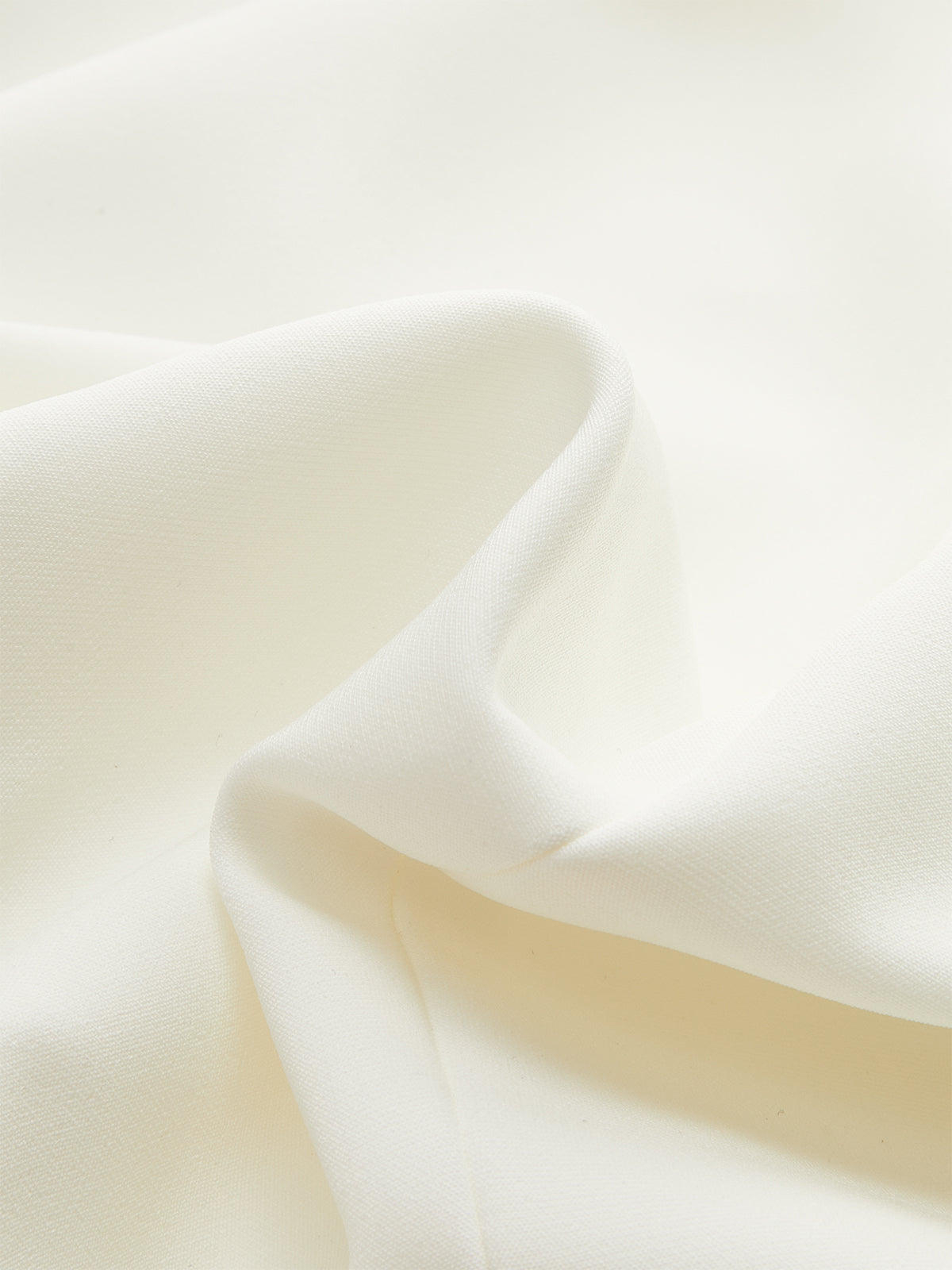 Wide-cut cropped blazer vest in soft white fabric, cinched waist, smooth gentle folds.
