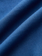 Blue beaded asymmetric sleeveless top with wrap-tie detail, detailed fabric weave visible.