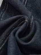 Dark indigo denim trousers with white contrast stitching, twill weave, and subtle slub texture.