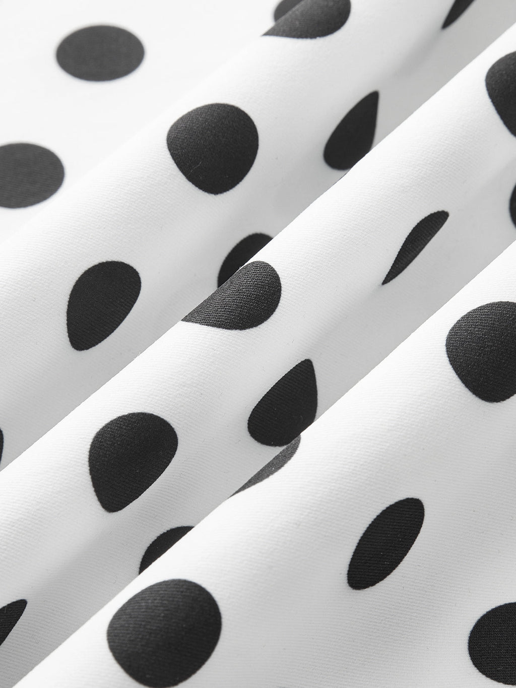 Sleeveless midi dress in white with black polka dots, elegant folds, and textured finish.