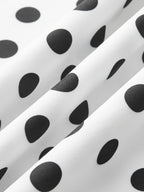 Sleeveless midi dress in white with black polka dots, elegant folds, and textured finish.