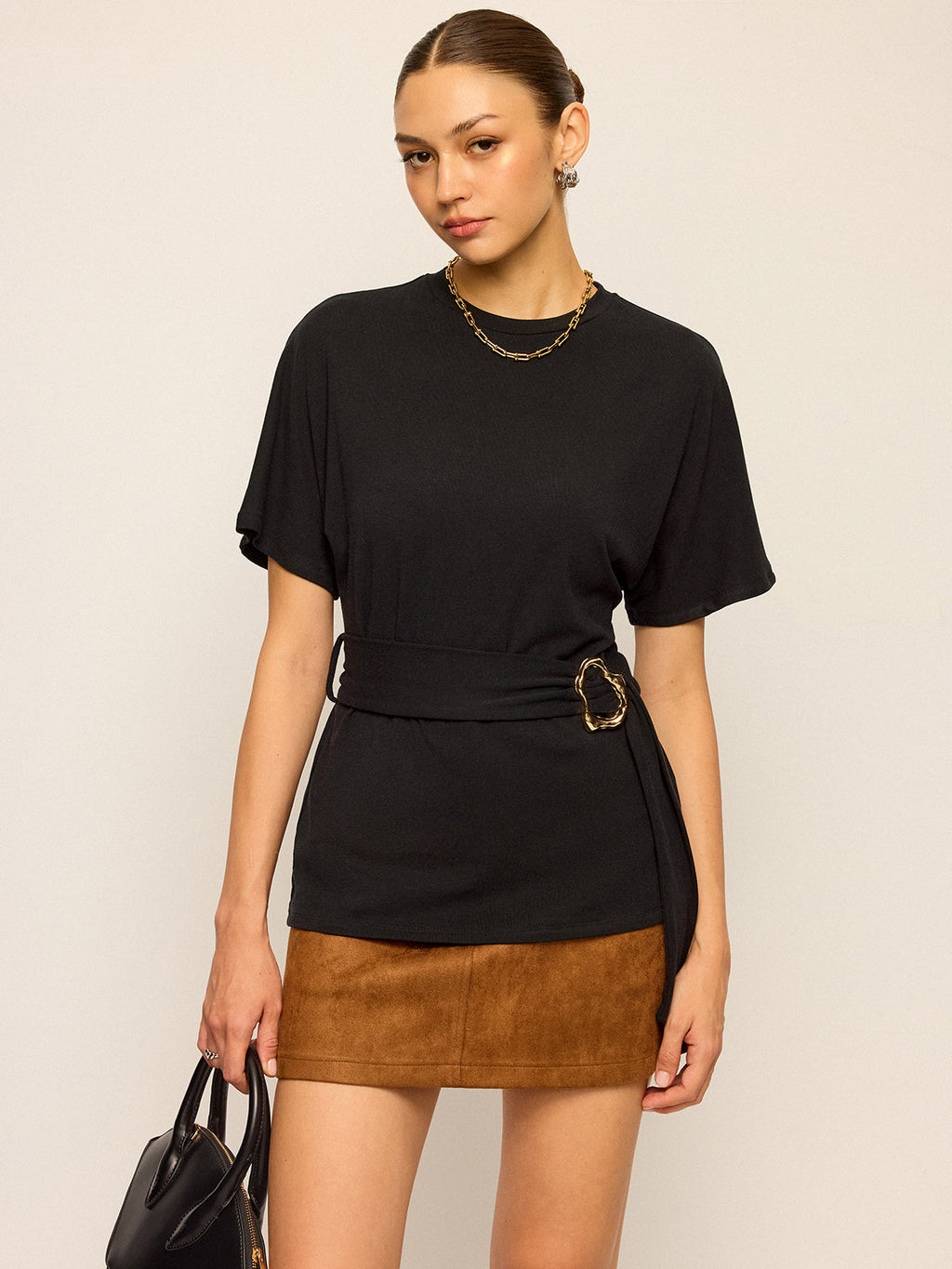 LA FINE FLEUR short-sleeve top with belt detail and brown suede mini skirt.