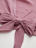 Dusty pink cropped tie-front blouse with long sleeves, textured cotton ridges, and a neat bow.
