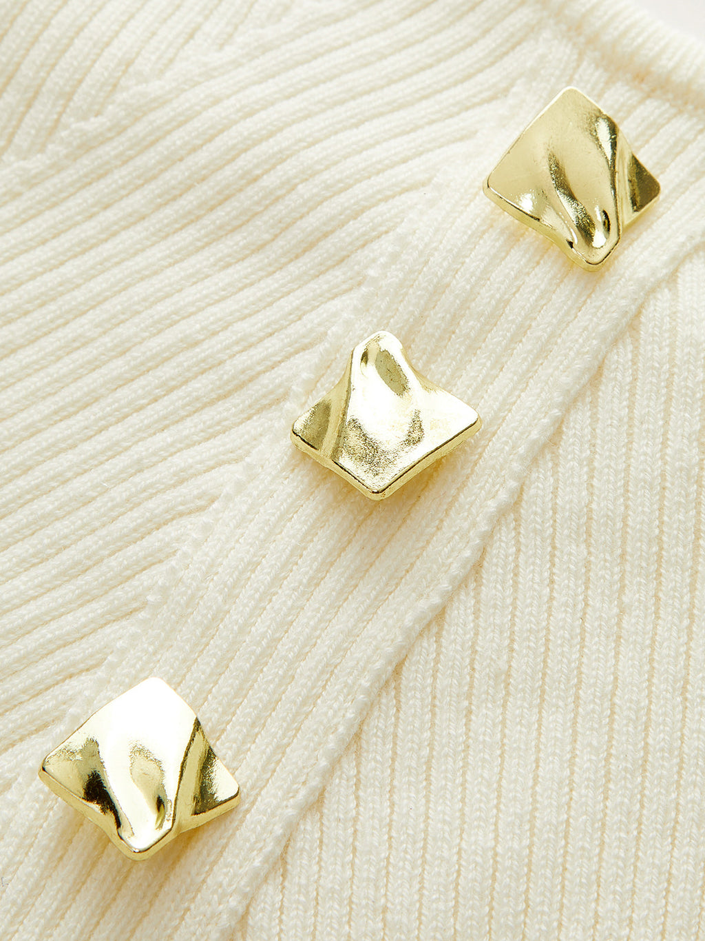 Cream ribbed knit cami top with three gold diagonal buttons, textured and slightly crumpled.