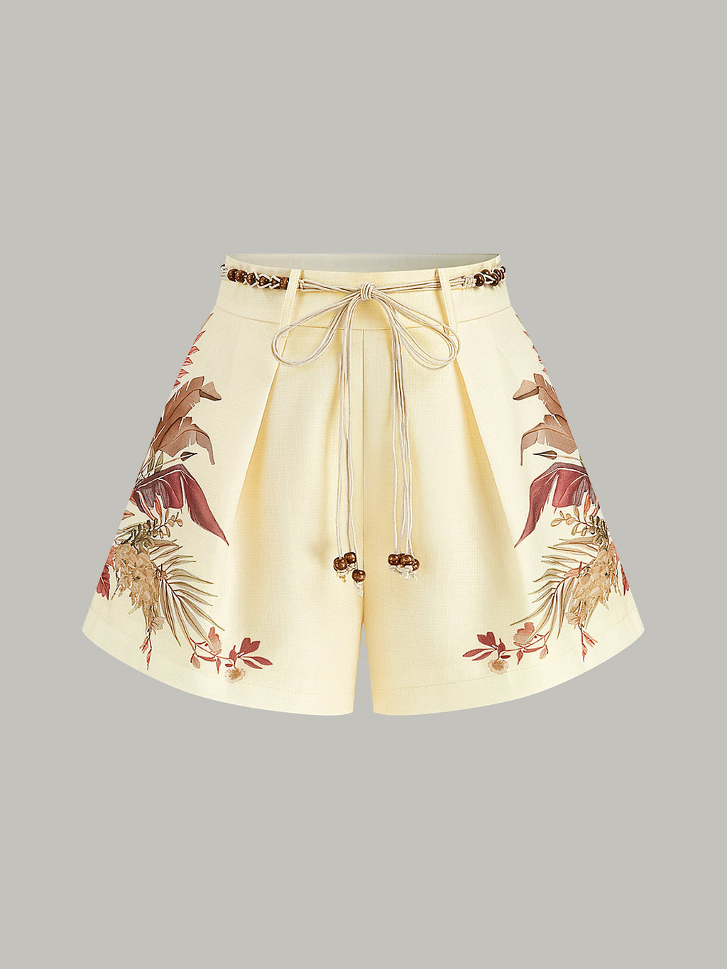 Cream mid-waist shorts with pleats, braided rope belt, and brown-beige floral hem pattern.