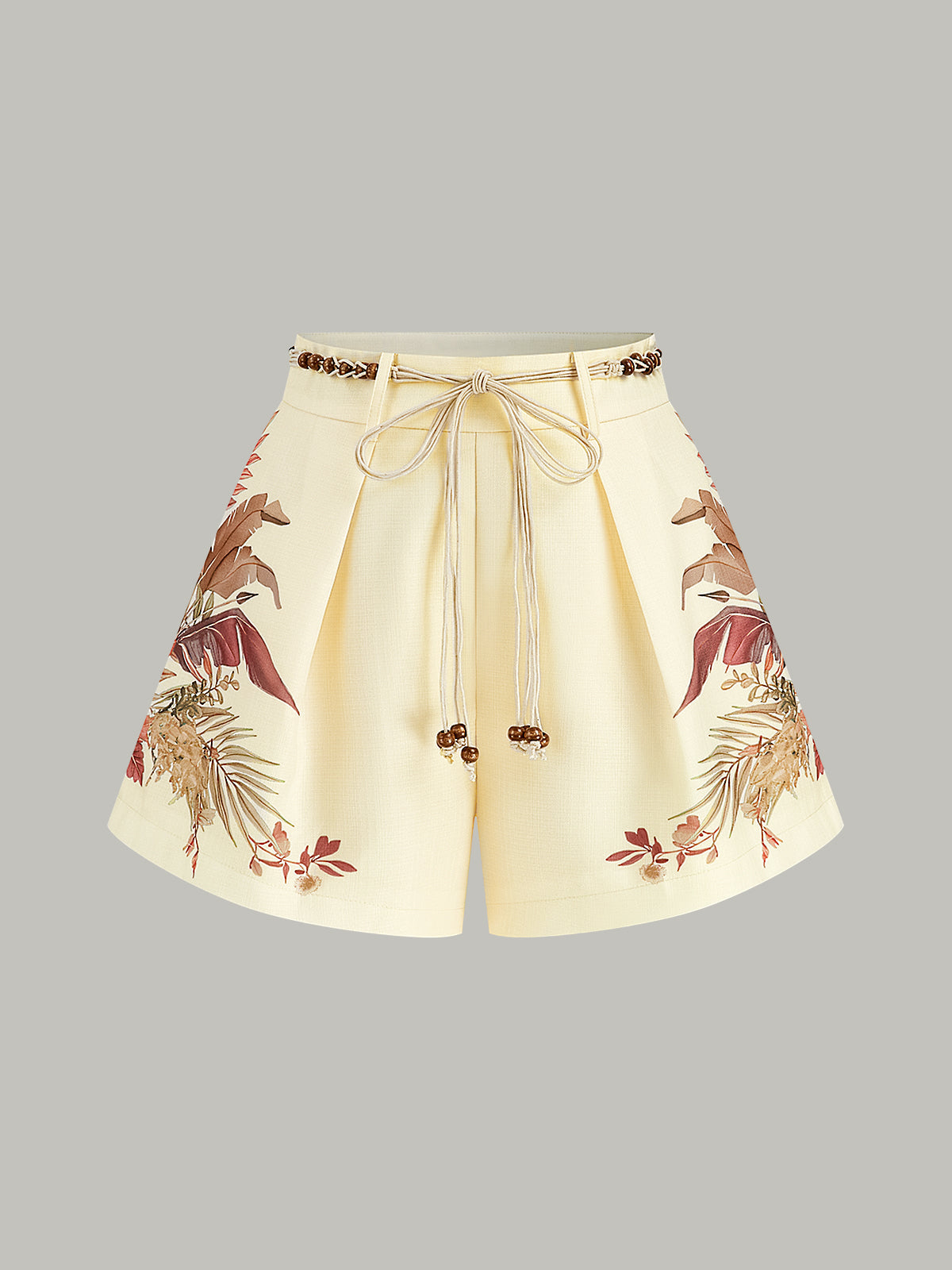 Cream mid-waist shorts with pleats, braided rope belt, and brown-beige floral hem pattern.