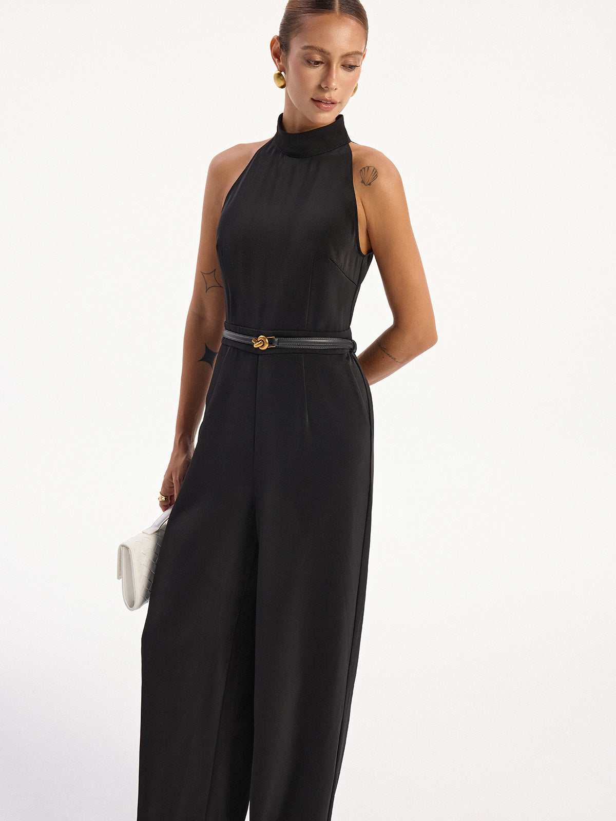 LA FINE FLEUR satin halter neck jumpsuit with back slit and black belt accent.