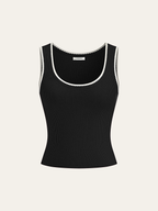 A black ribbed knit tank top with scalloped white trim at the neckline and armholes.